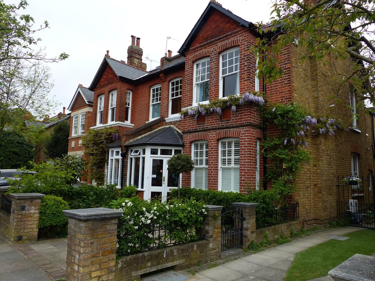 Red-brick Edwardian houses with front gardens on a suburban street