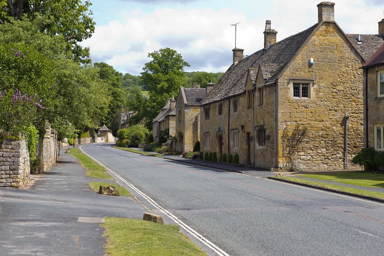 A quiet village road between stone cottages and a grass verge